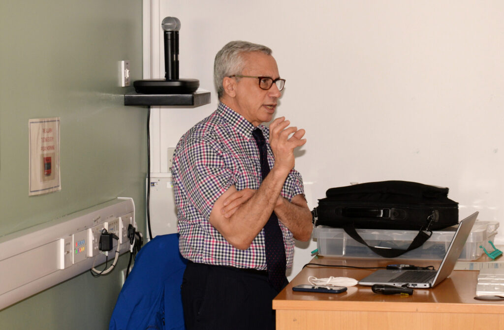 A faculty member speaking at the front of the lecture room