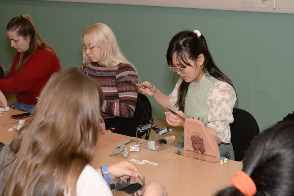 Delegates practising repairs on perineal trainer models