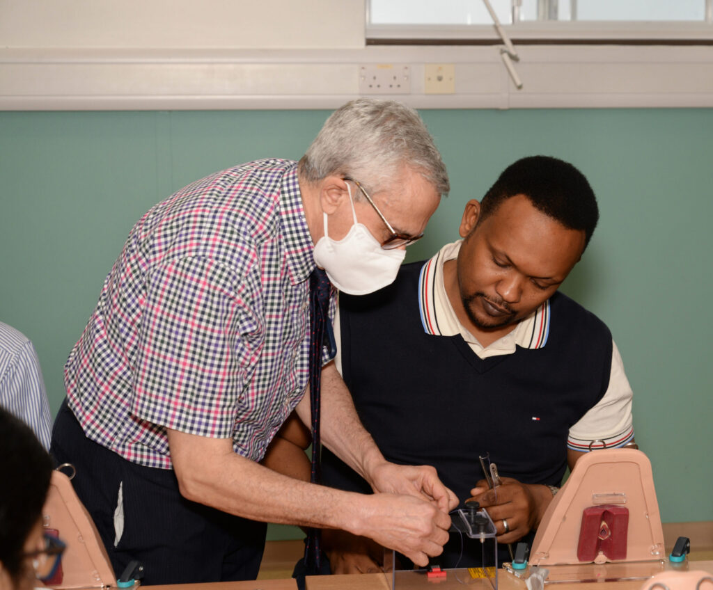 A faculty member guiding a delegate at a perineal trainer