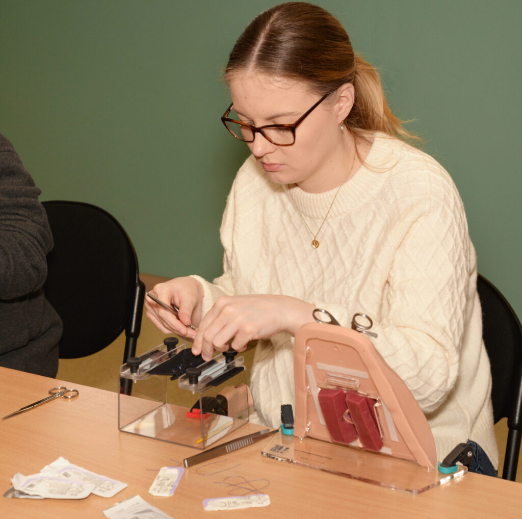 A delegate working on a perineal trainer with surgical instruments