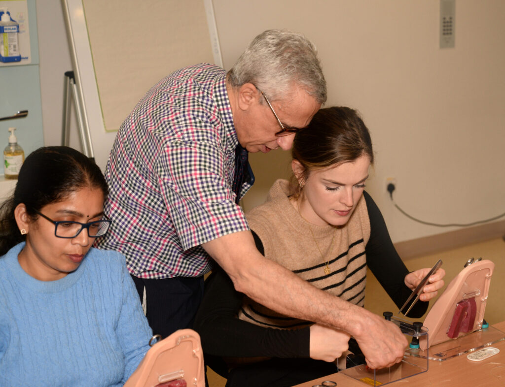 A faculty member showing two delegates how to place a suture