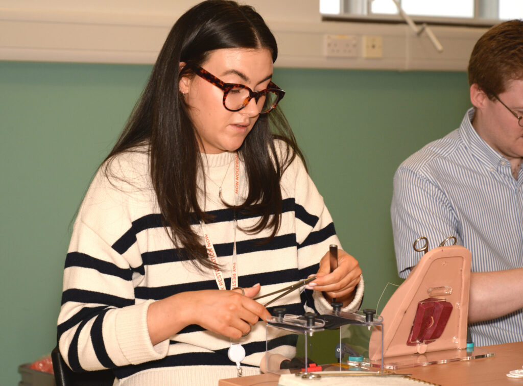 A delegate suturing on a perineal trainer