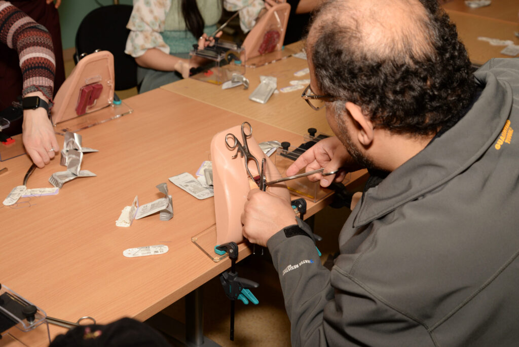 A delegate tying a suture on a perineal trainer