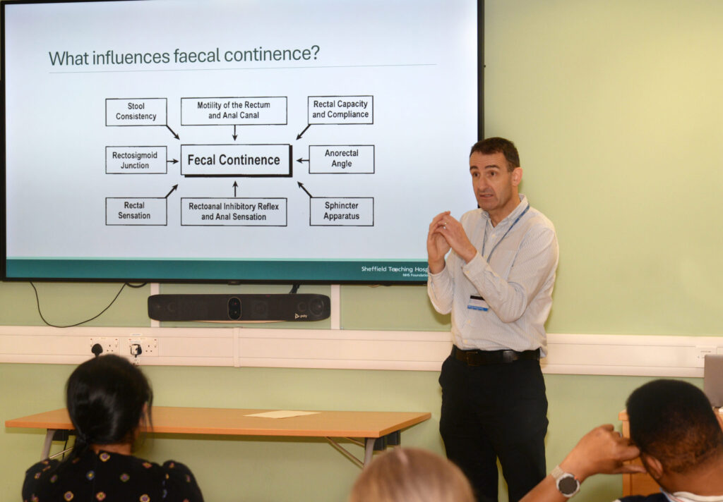 A speaker presenting a slide on faecal continence